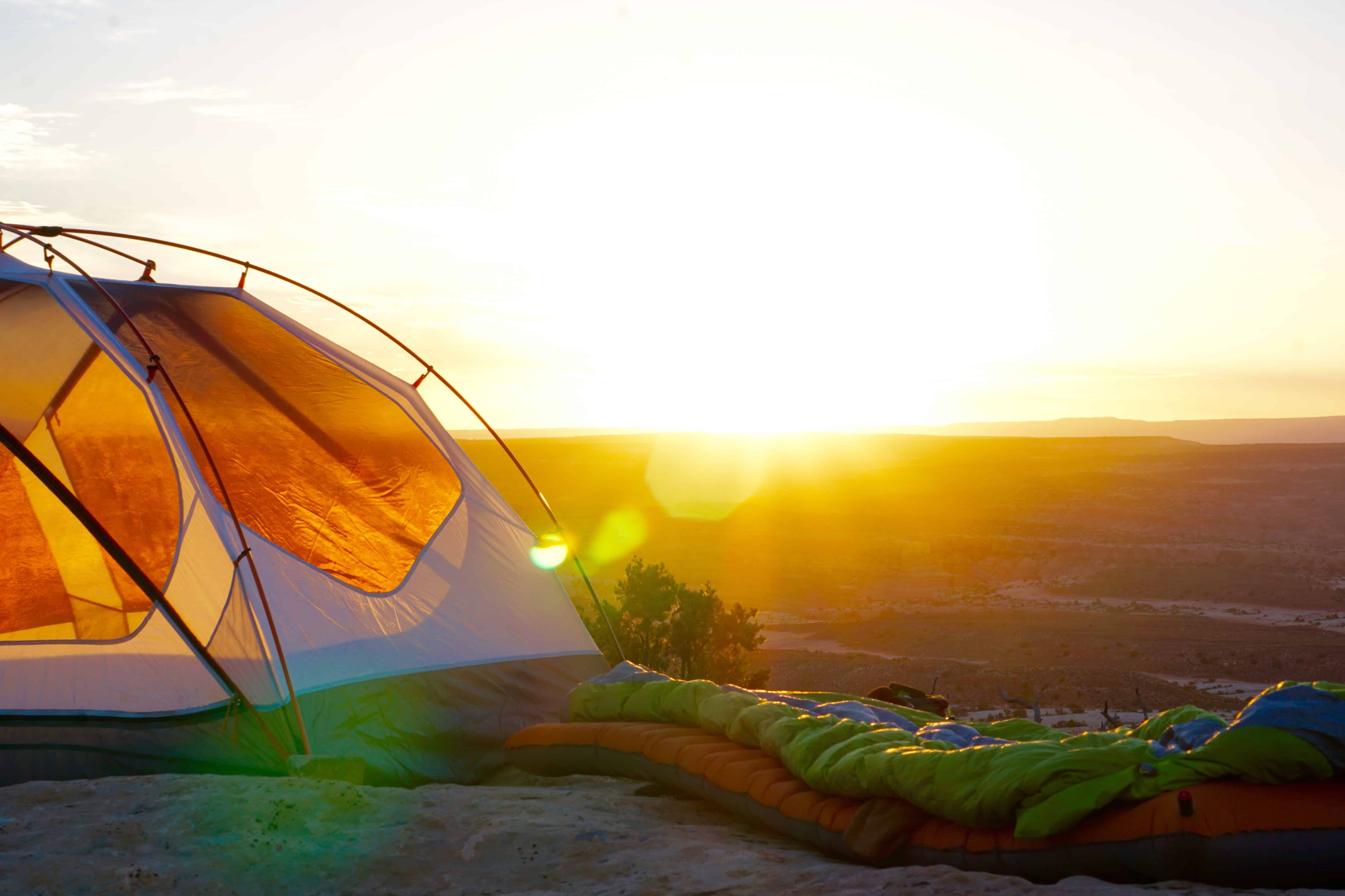 a camping tent in a field at sunset