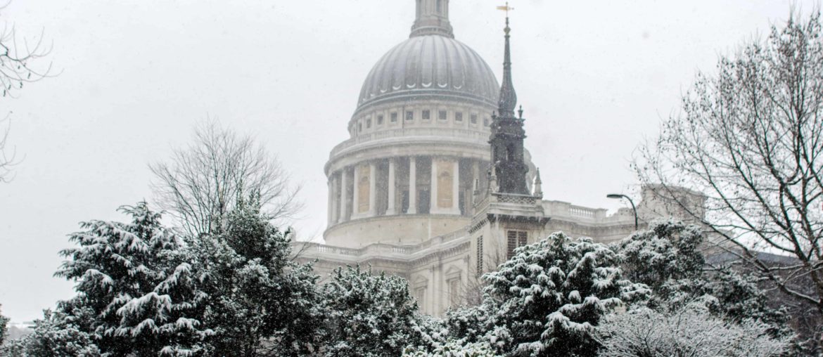 dome of st pauls above snow-covered trees in london