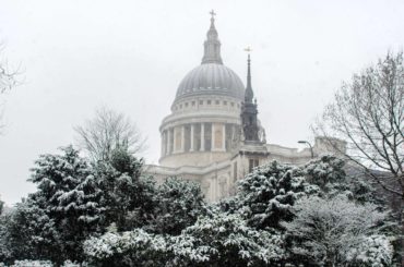 dome of st pauls above snow-covered trees in london