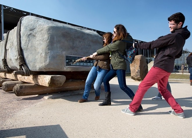 a group of visitors to stonehenge try and pull a sarsen megalith