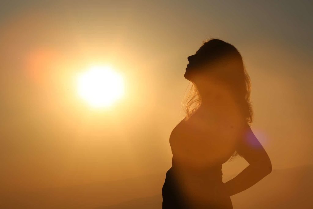 a silhouette of a woman relaxing as the sun sets behind her
