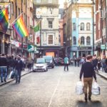 Shoppers walking down a Soho street in London's westend past a bar with a LGBT rainbow flag