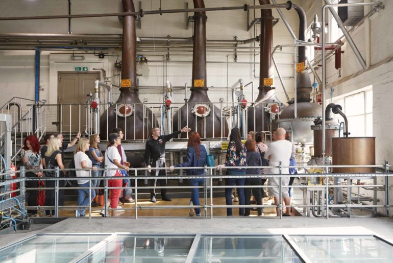 tour group next to copper stills at the beefeater gin distillery tour in london