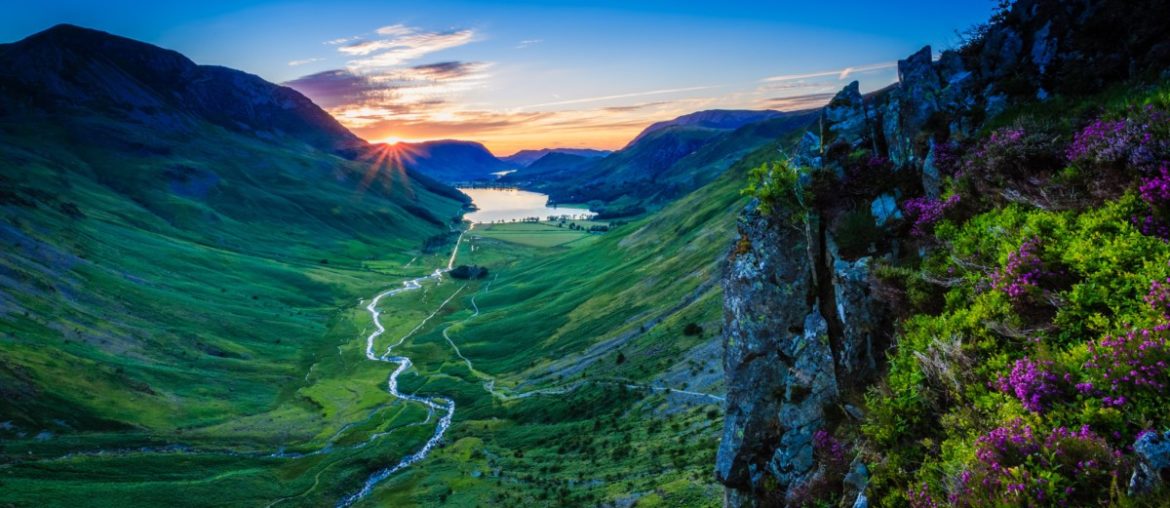 sun setting in the distance behind the mountains of the lake district