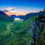 sun setting in the distance behind the mountains of the lake district