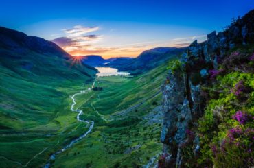 sun setting in the distance behind the mountains of the lake district