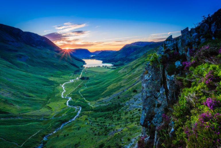 sun setting in the distance behind the mountains of the lake district
