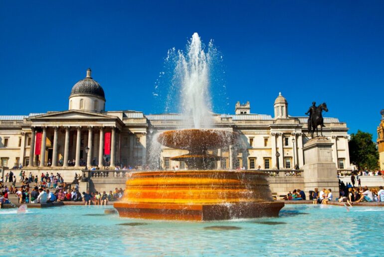 photo of the national gallery in trafalgar square with a fountain in the center
